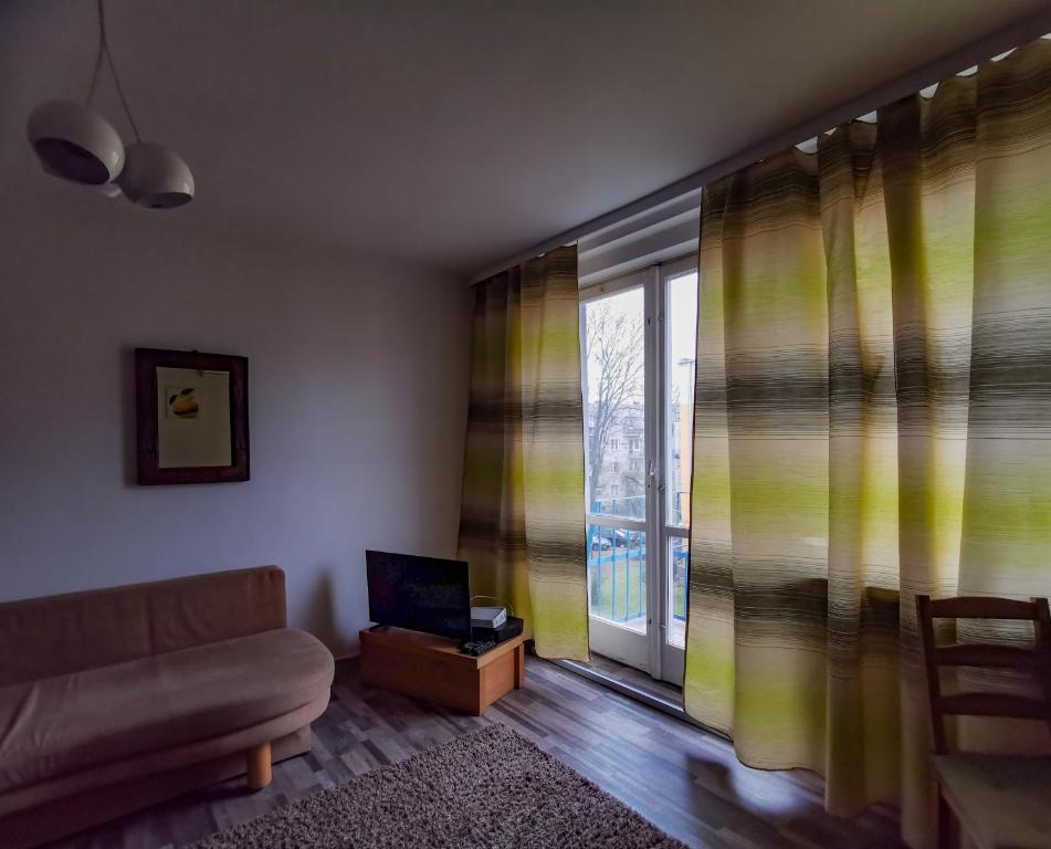 a living room with a couch and a window at Velvet Trojdena in Warsaw