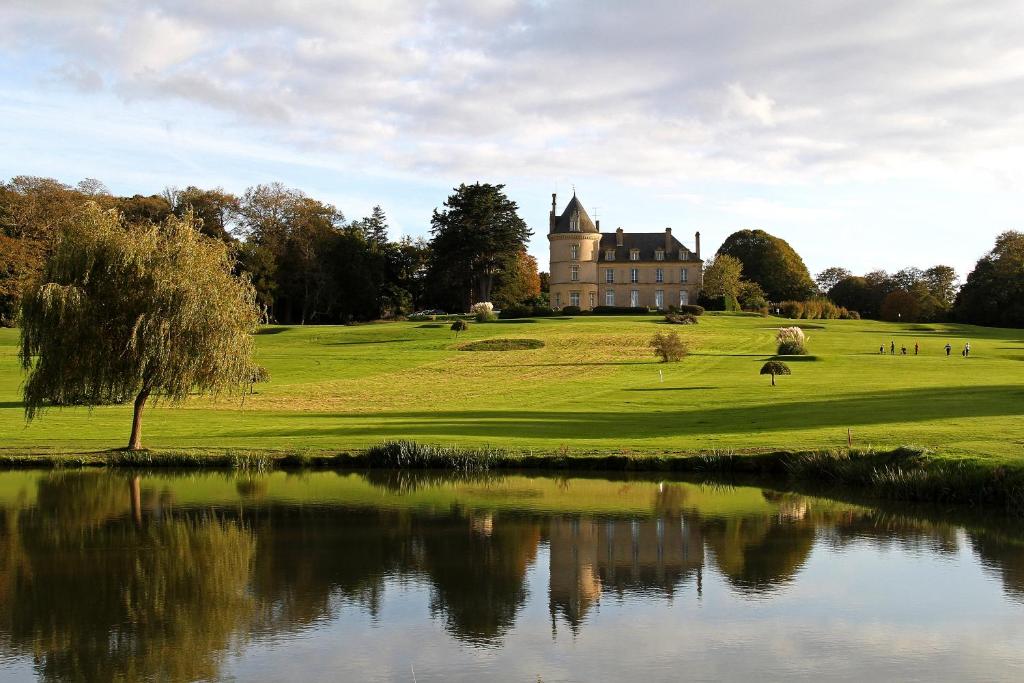 een kasteel op een heuvel met een vijver ervoor bij Hôtel de Boisgelin in Pléhédel