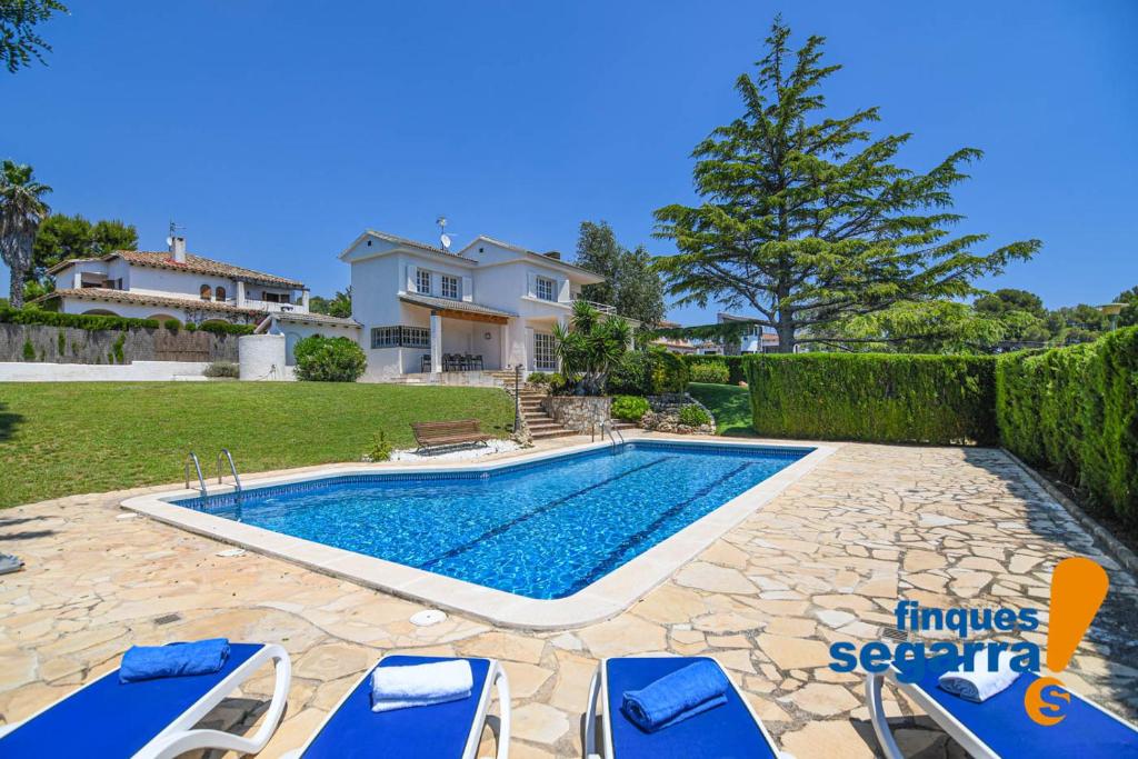 una piscina con sedie e una casa di Villa Angels a El Vendrell