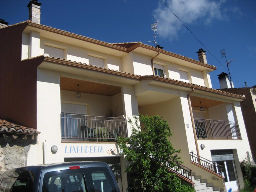 a white house with a car parked in front of it at Apartamentos Rascafria Cerquilla in Rascafría