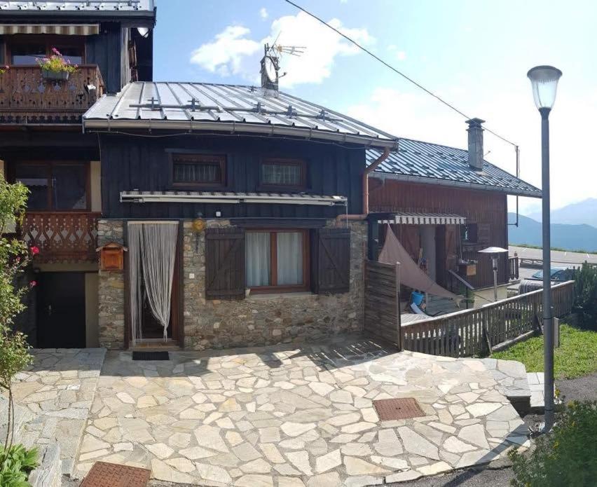 a house with a stone patio in front of it at Chalet de montagne au cœur de Doucy in Doucy