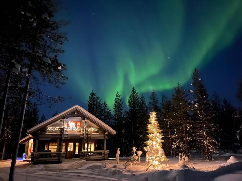 a cabin with a christmas tree and the aurora at Luoston Väärtin Kammi in Luosto