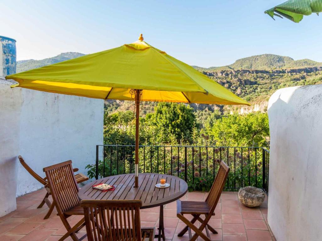 a table with a yellow umbrella on a patio at Casa peñuela in Albuñuelas