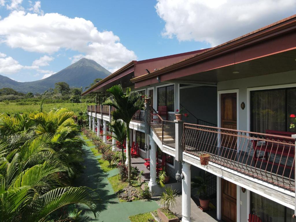 a house with a balcony with a mountain in the background at Campos Arenal Hotel in Fortuna