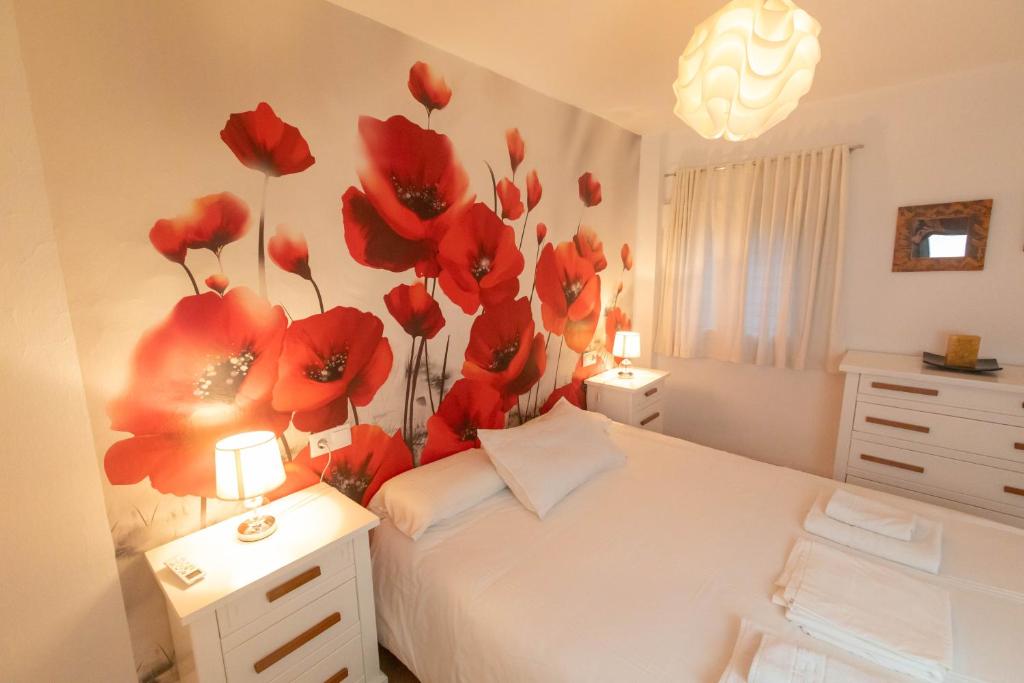 a bedroom with a bed with red flowers on the wall at Casa de las Flores Cazorla in Cazorla
