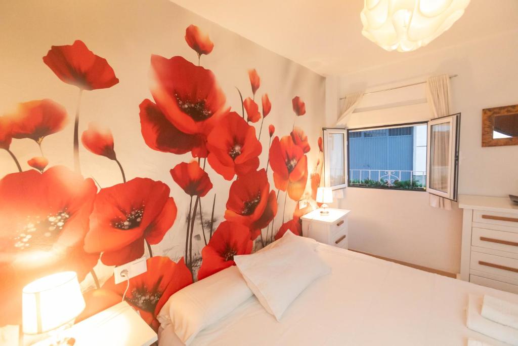 sypialnia z czerwonymi kwiatami na ścianie w obiekcie Casa de las Flores Cazorla w mieście Cazorla