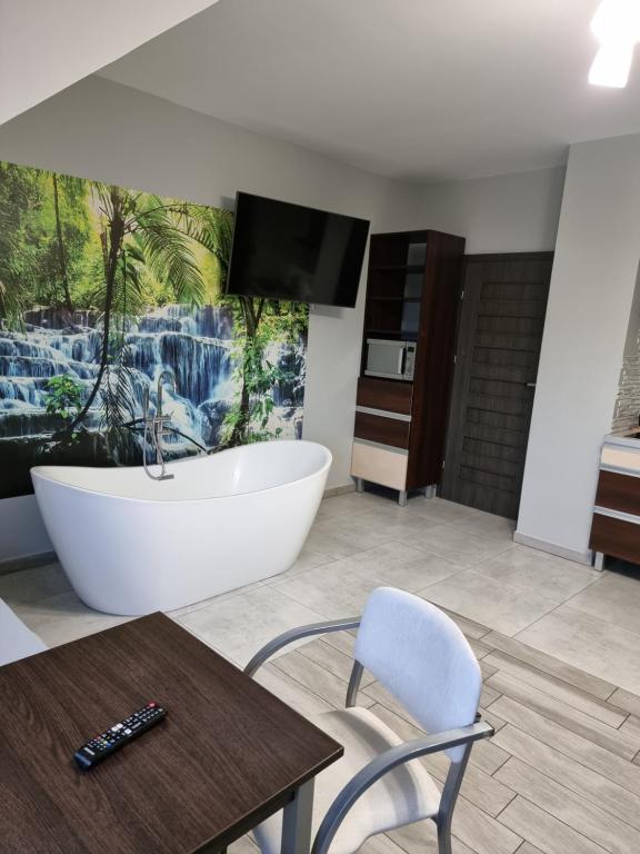 a bathroom with a tub and a tv and a table at Noclegi 24/h Leszczynek in Kutno