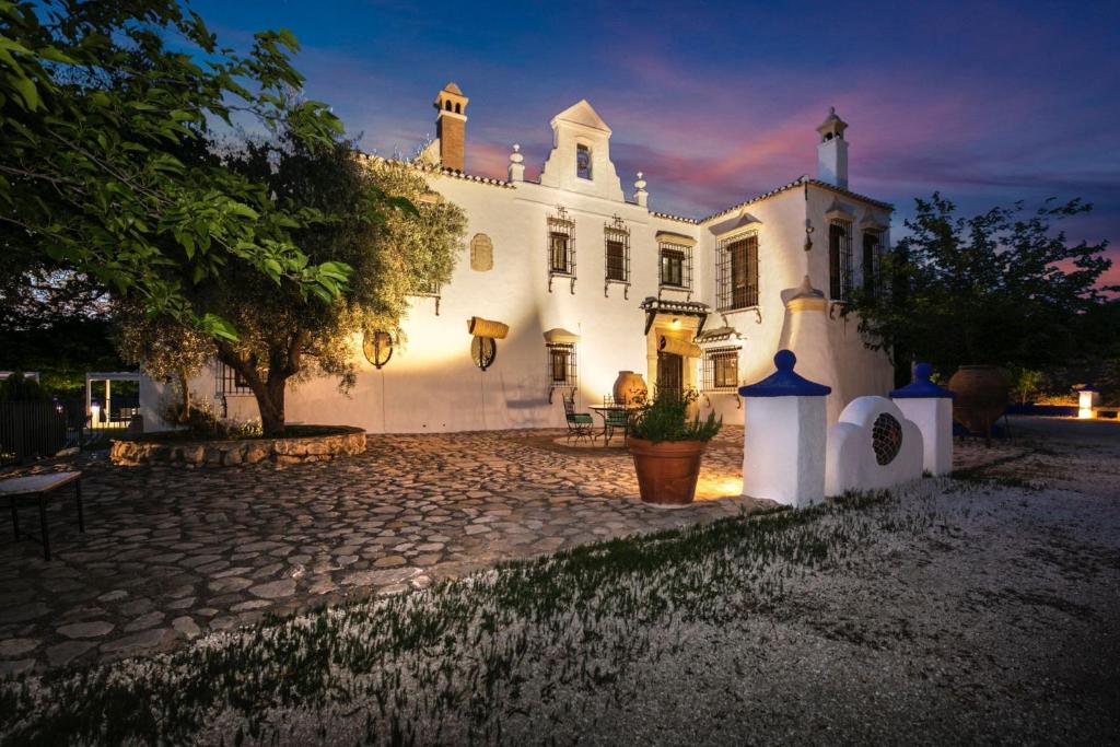 a large white house with a cobblestone driveway at Cortijo el Zafiro in Montefrío