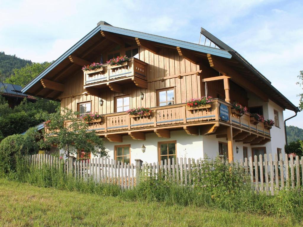 ein Holzhaus mit Balkon und einem Zaun in der Unterkunft Schmuckhäusl in Reit im Winkl