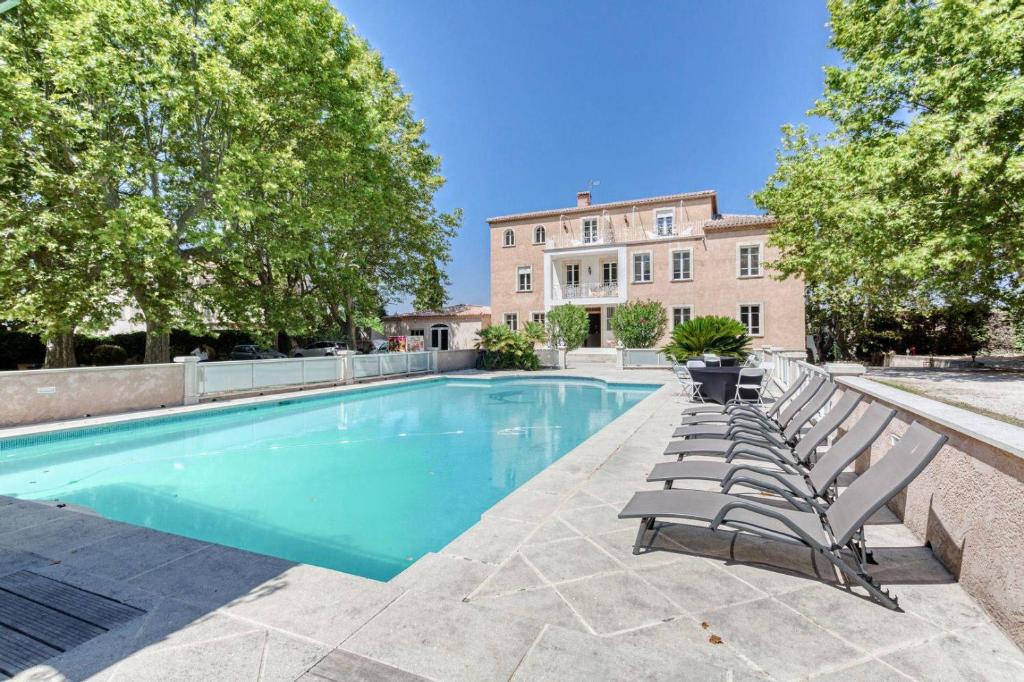 a swimming pool with lounge chairs and a building at DOMAINE DE LA NERTHE- HOTEL PROVENCE MEDITERRANEE in Gignac-la-Nerthe