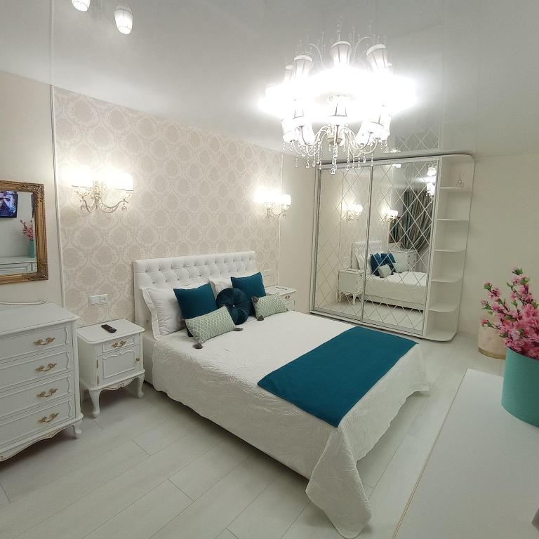 a bedroom with a bed with a mirror and a chandelier at VIP Апартаменти in Dnipro