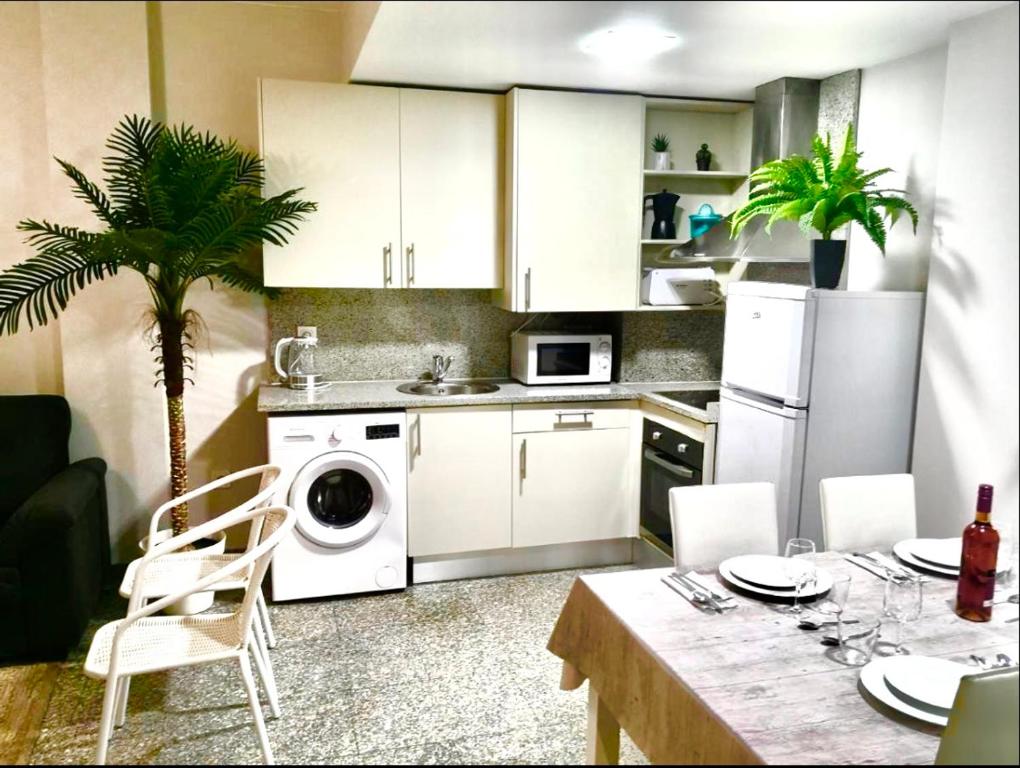a kitchen with white cabinets and a table with a plant at SeaHomes Vacations, BEACH&POOL, in Fenals Beach in Lloret de Mar