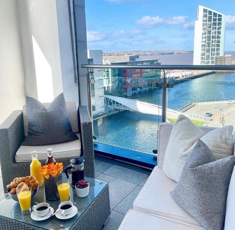 a balcony with a table with drinks and a view of the water at NOVU Apartments Liverpool Waterfront in Liverpool