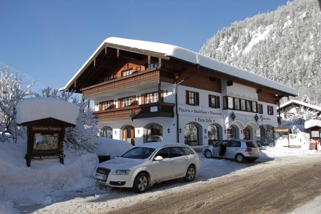 ein großes Gebäude mit davor geparkt in der Unterkunft Gästehaus Angerer in Reit im Winkl