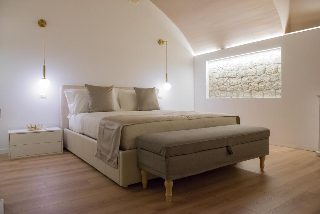 POSA - Charming Rooms في أكوافيفا ديلي فونتي: غرفة نوم بيضاء مع سرير ومقعد