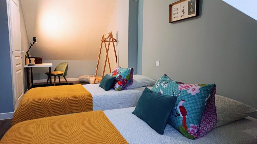 - une chambre avec deux lits, une table et une chaise dans l'établissement Maison Cosy La Jolie Fécampoise, à Fécamp