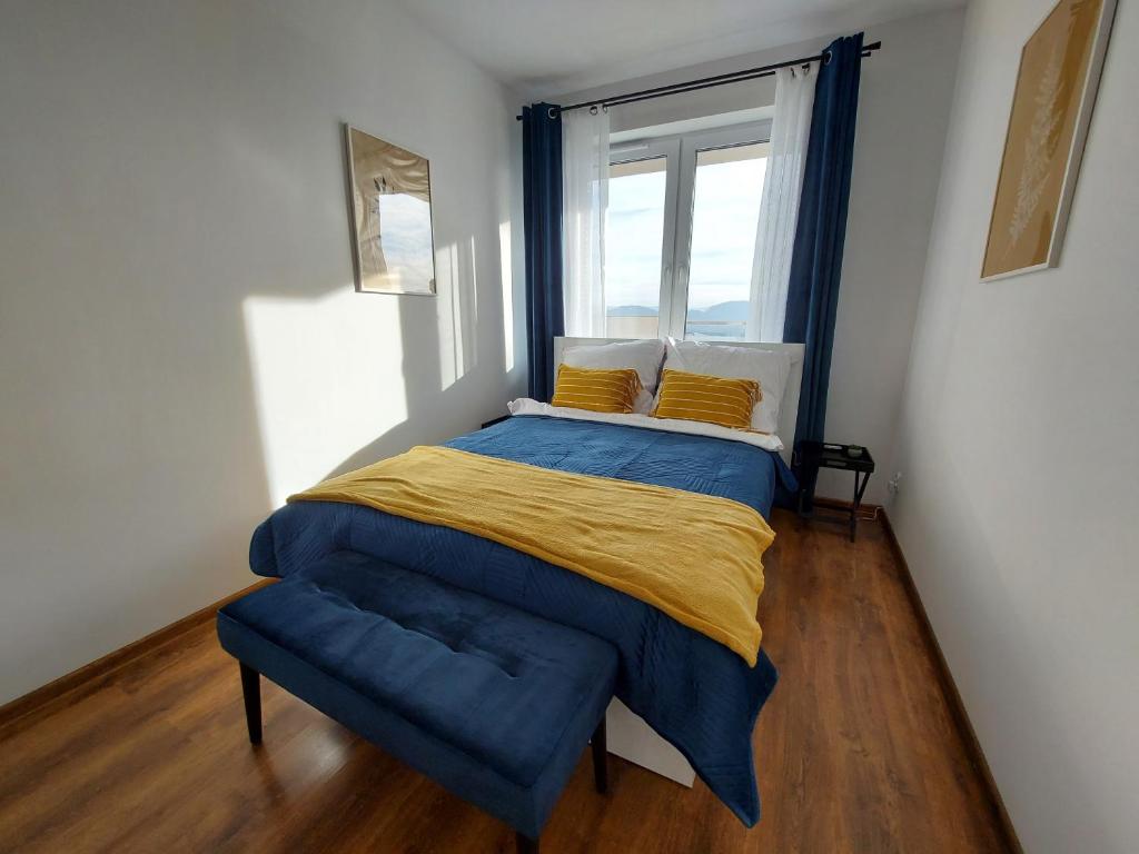 a bedroom with a bed with a blue blanket and a window at Allewidok in Jelenia Góra