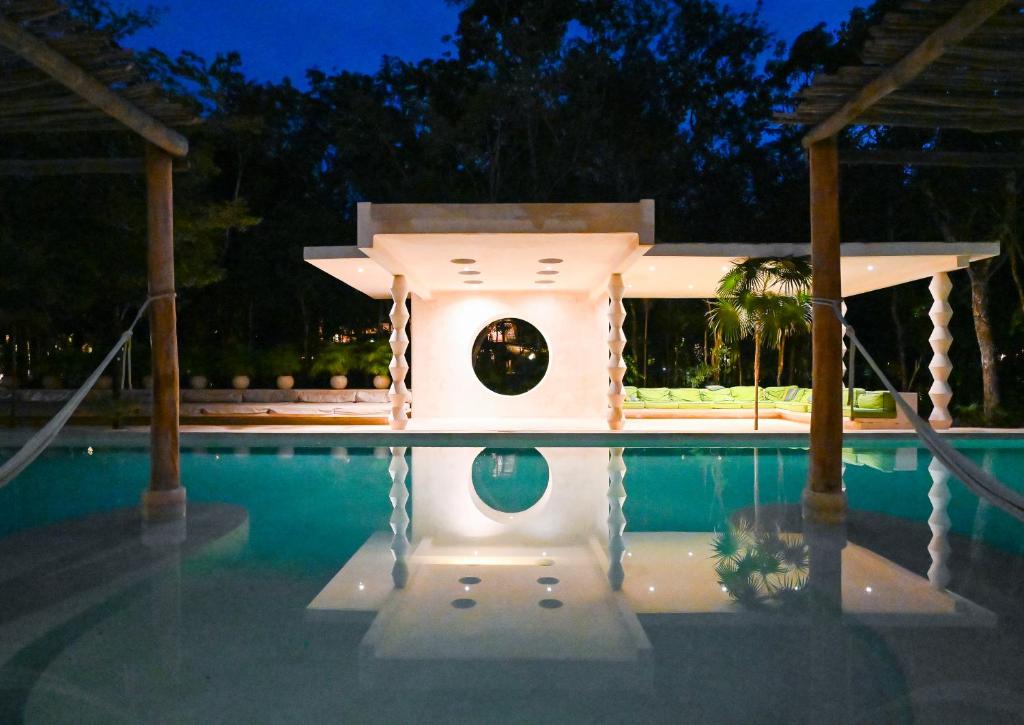 a house in the middle of a pool at night at Hotel Holistika Tulum in Tulum