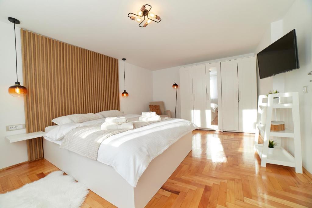 a white bedroom with a large bed and a flat screen tv at Schei Residence in Braşov