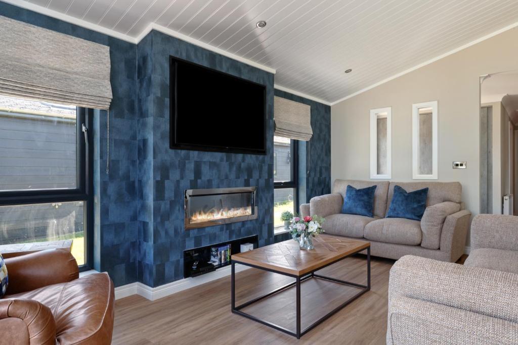 a living room with a couch and a fireplace at Dewin Bach - Luxury Lodge, Hot Tub, Close to Beach in Penally