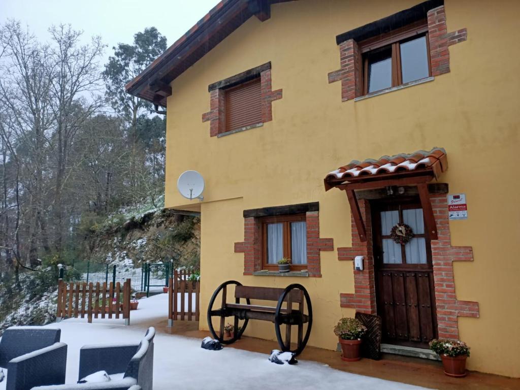 a yellow house with snow on the porch at Carroceu Rural in Cangas de Onís