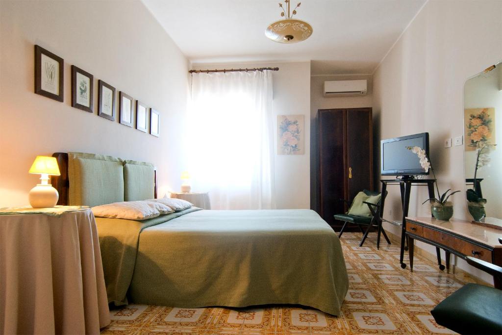 Dormitorio con cama, escritorio y TV en Mimì Rooms, en Cagliari
