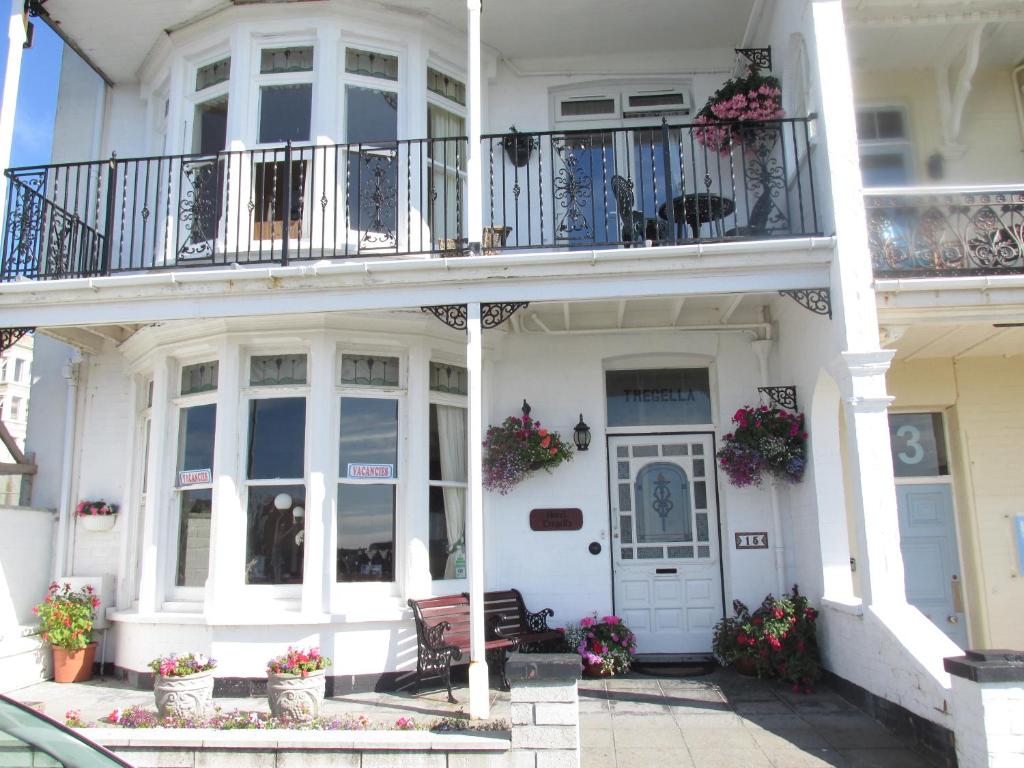 a white house with a balcony and a porch at Tregella Guest House in Newquay