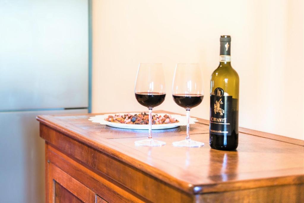 una botella de vino y dos copas de vino en una mesa en Hostly - La Pera Suite Apartment - 2 Bedrooms, Full Center, en Pisa