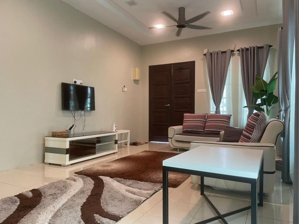 a living room with a couch and a tv at VISTANA INDAH HOMESTAY in Alor Setar