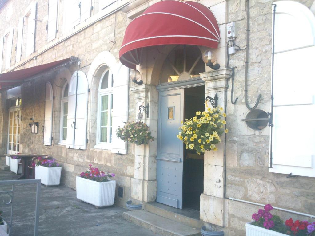 ein Gebäude mit Topfpflanzen auf der Vorderseite in der Unterkunft Hôtel de L'Europe in Gramat
