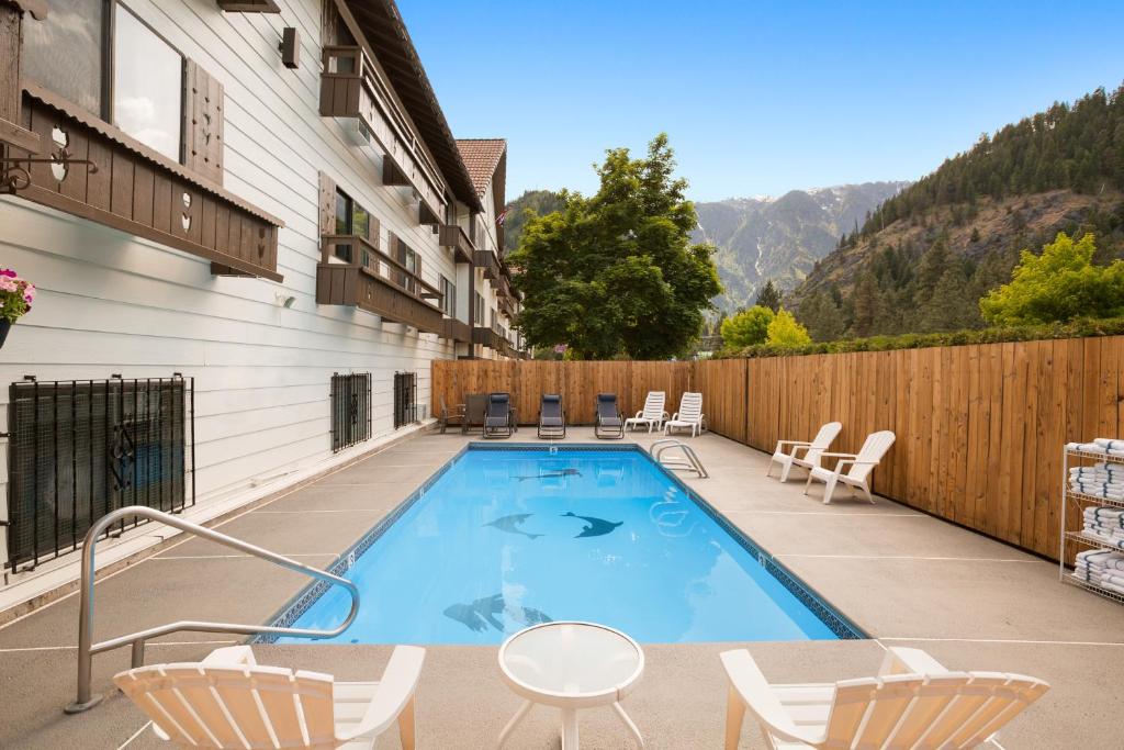 a swimming pool with chairs and a fence at Howard Johnson by Wyndham Leavenworth in Leavenworth