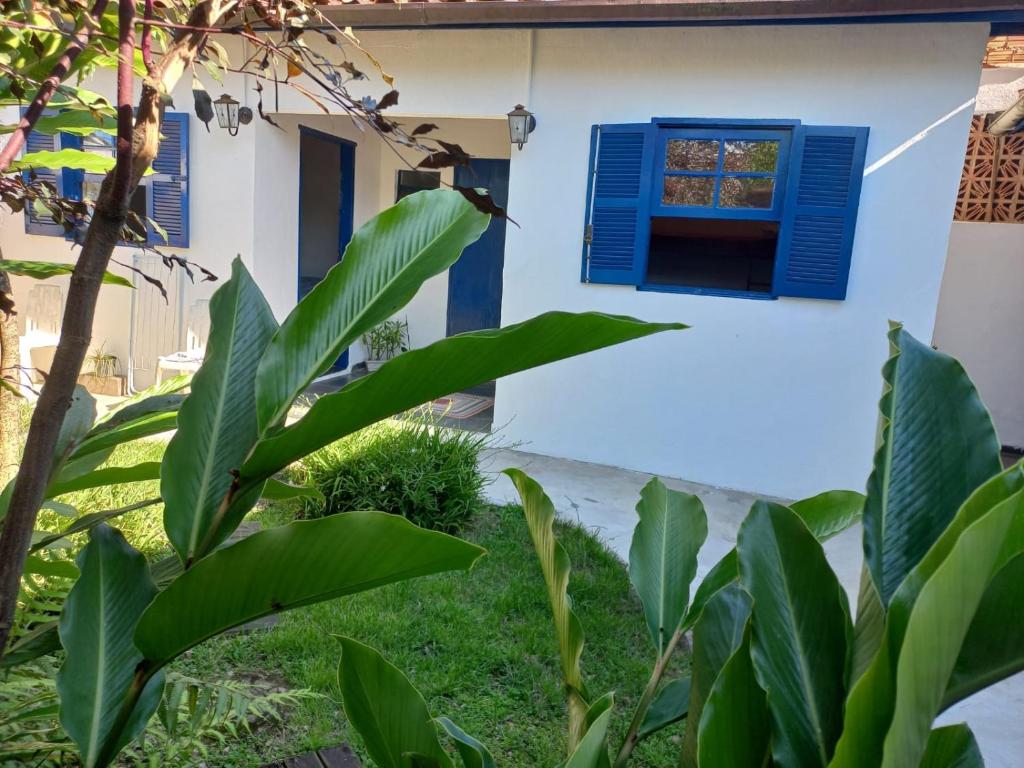 uma casa com uma janela azul e plantas verdes em Edícula Simples, prático e ideal em Ilhabela
