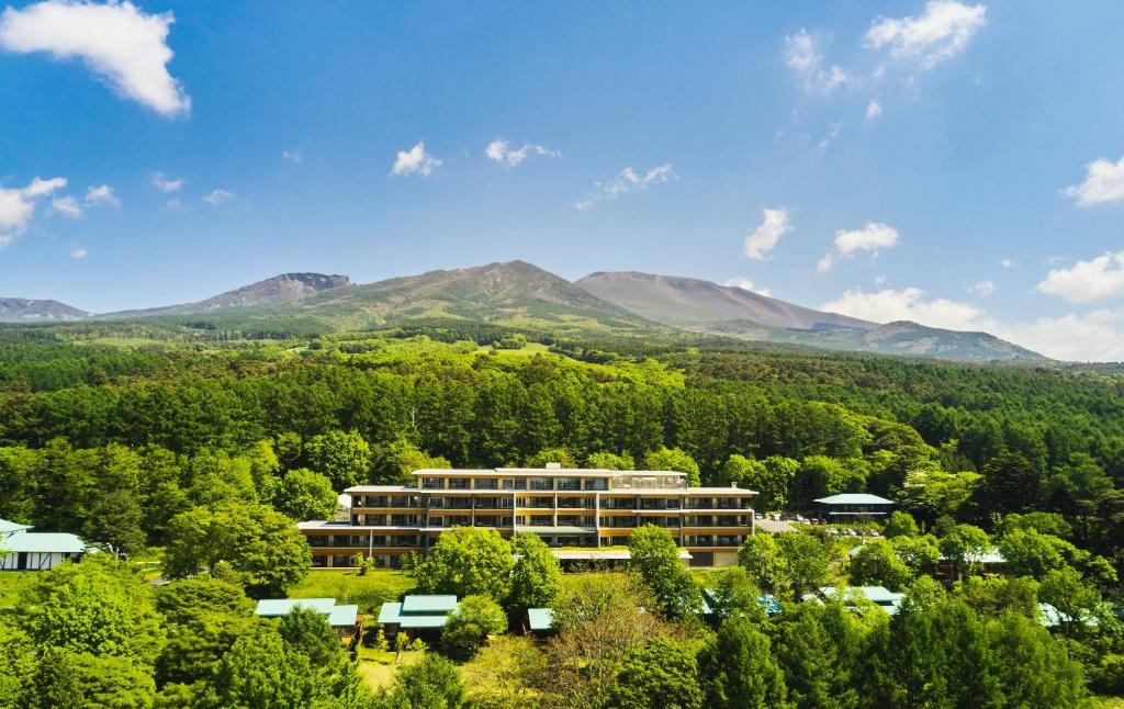 een gebouw midden in een bos met bergen bij THE HIRAMATSU KARUIZAWA MIYOTA in Miyota