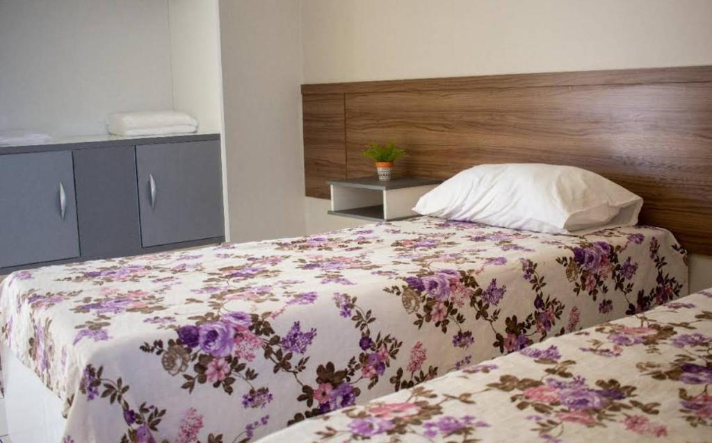a bedroom with a bed with a floral bedspread at Cantinho do Brejo Pousada in Guarabira