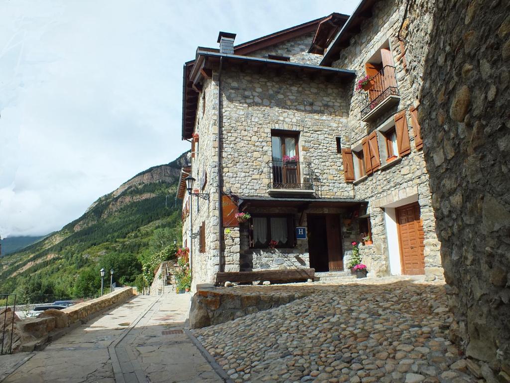 a stone building on a street with mountains in the background at Hotel Areulo in Cerler