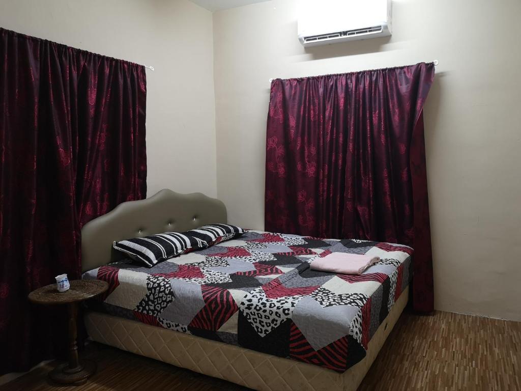 a bedroom with a bed with red curtains at Babamoon Homestay in Melaka