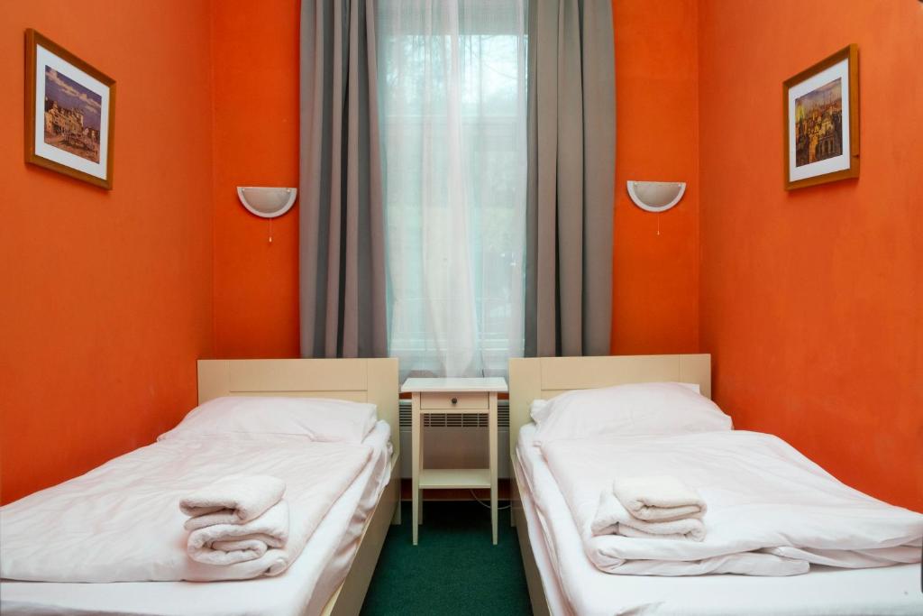 two beds in a room with orange walls at Hotelové Pokoje Kolčavka in Prague