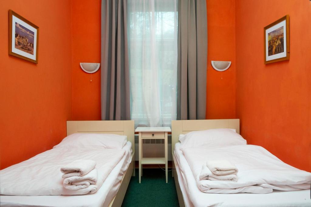 two beds in a room with orange walls at Hotelov&eacute; Pokoje Kolčavka in Prague