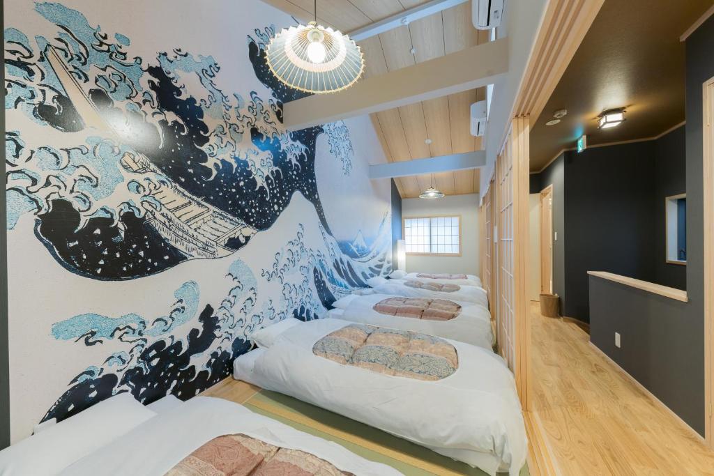 a row of beds in a room with a wave mural at YADOYA 根岸 in Tokyo
