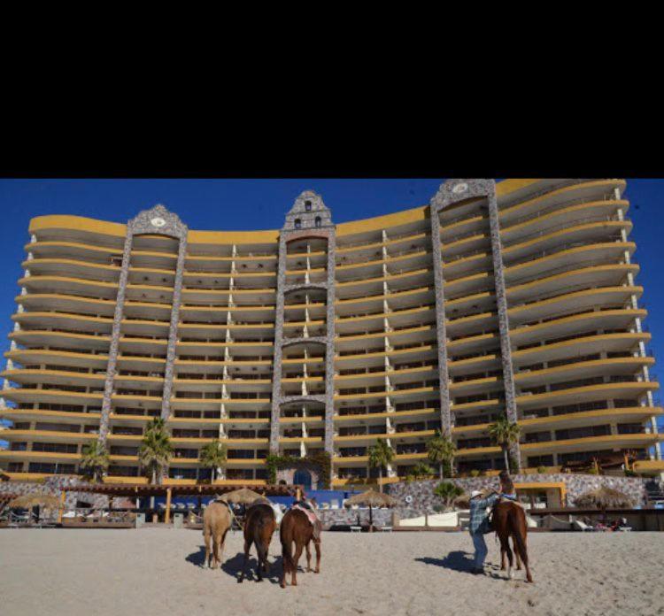 a hotel on the beach with horses in front of it at Sonoran Sky Resort Oceanview Condo in Puerto Peñasco