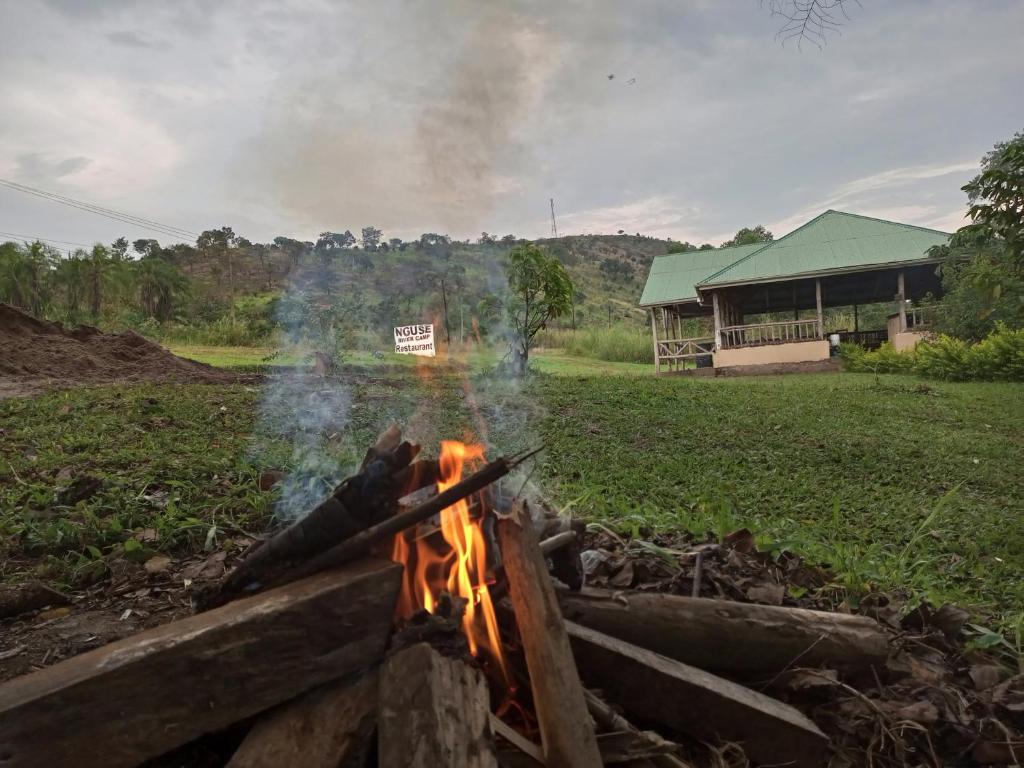 a fire in a field with a building in the background at Nguse River Camp in Kikube