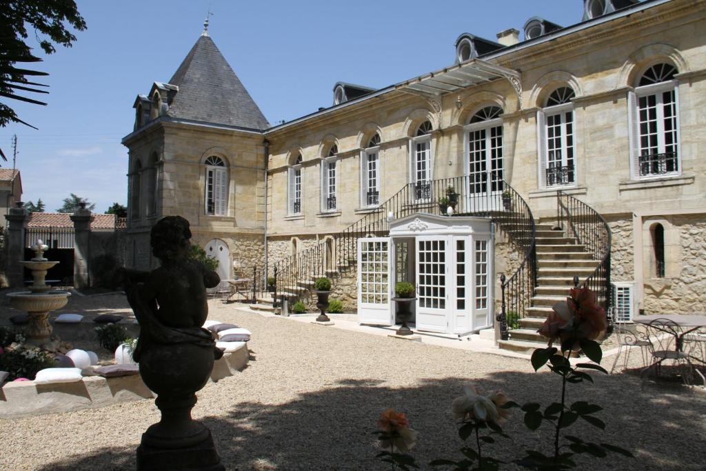 un gran edificio con una estatua delante de él en Chambres d'Hotes La Chartreuse des Eyres, en Podensac