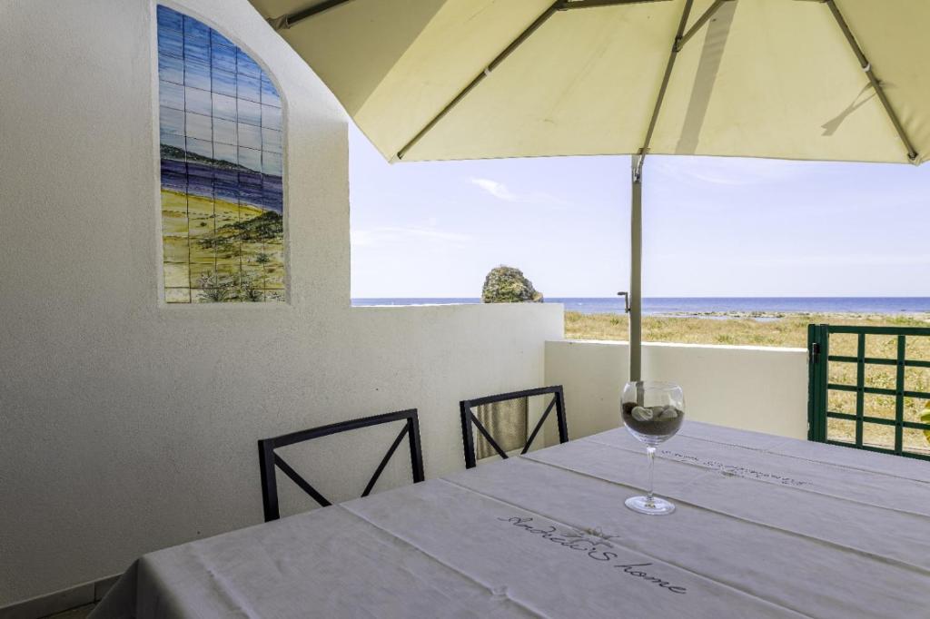 un tavolo con bicchiere da vino e ombrellone di Andrew'S home - Playita a Torre Pali
