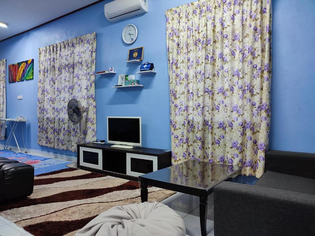 uma sala de estar com uma parede azul com cortinas e uma televisão em Riverview Homestay - Homestay Tepi Sungai Golok em Rantau Panjang