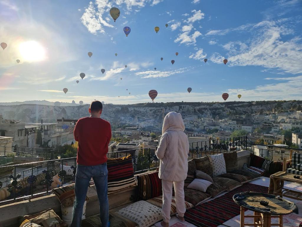 Ein Mann und eine Frau stehen auf einem Balkon mit Blick auf Heißluftballons in der Unterkunft Vineyard Cave Hotel in Goreme