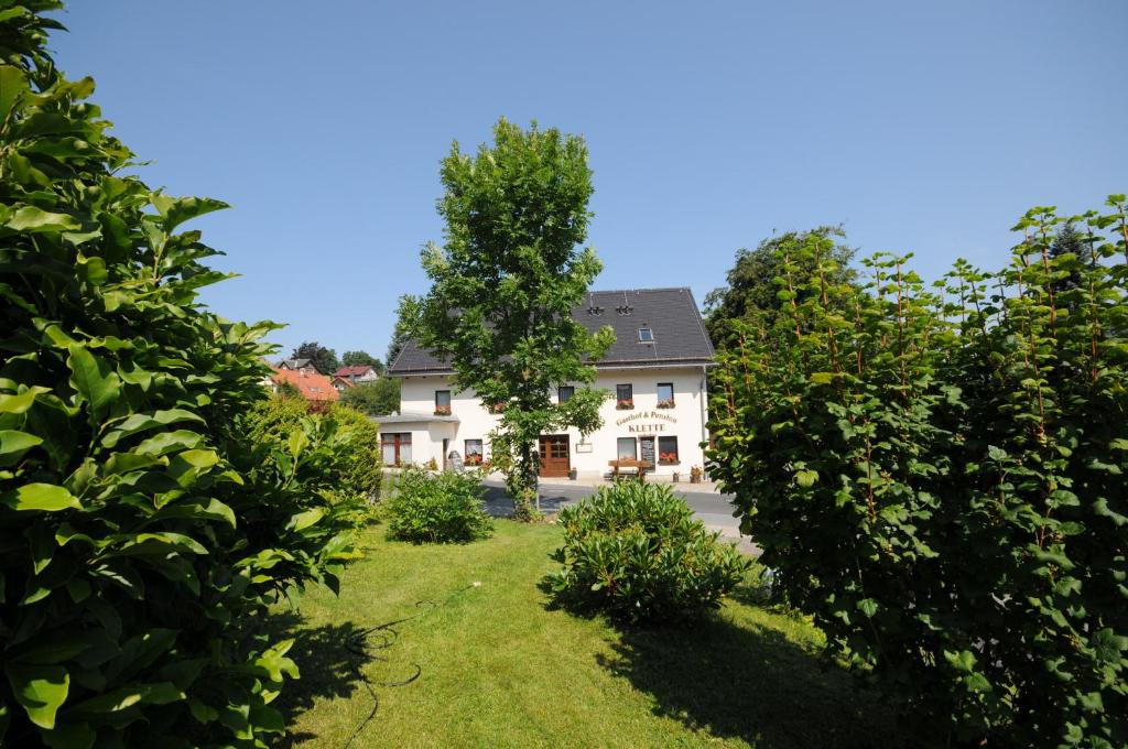 een groot wit huis met een boom in de tuin bij Pension Klette in Kurort Oybin