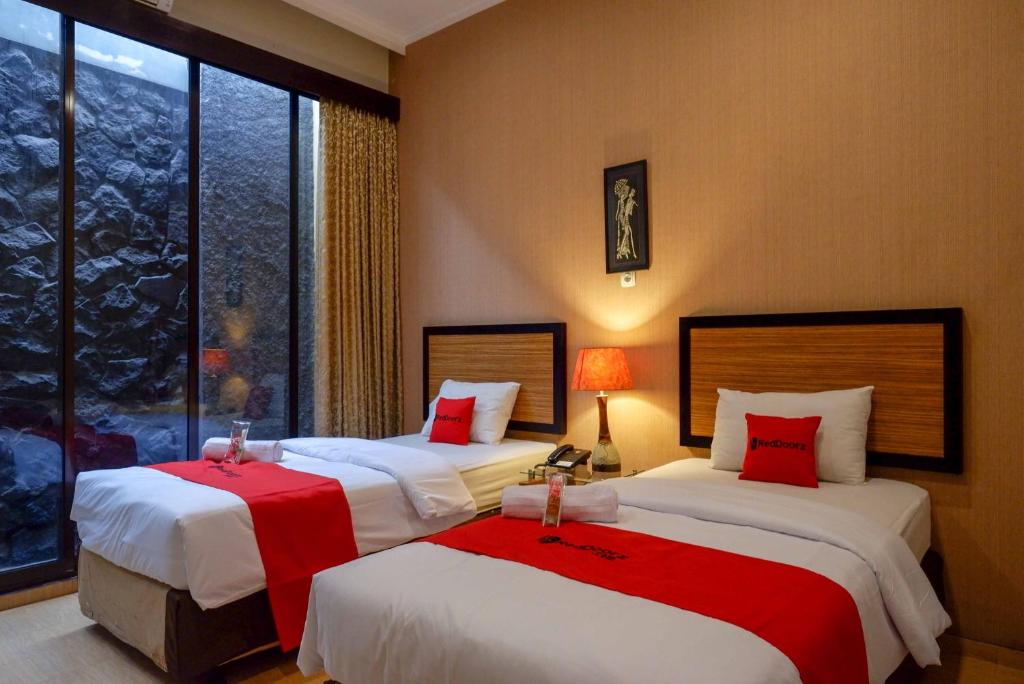 a hotel room with two beds with red pillows at RedDoorz Plus near Amplaz Yogyakarta in Demangan