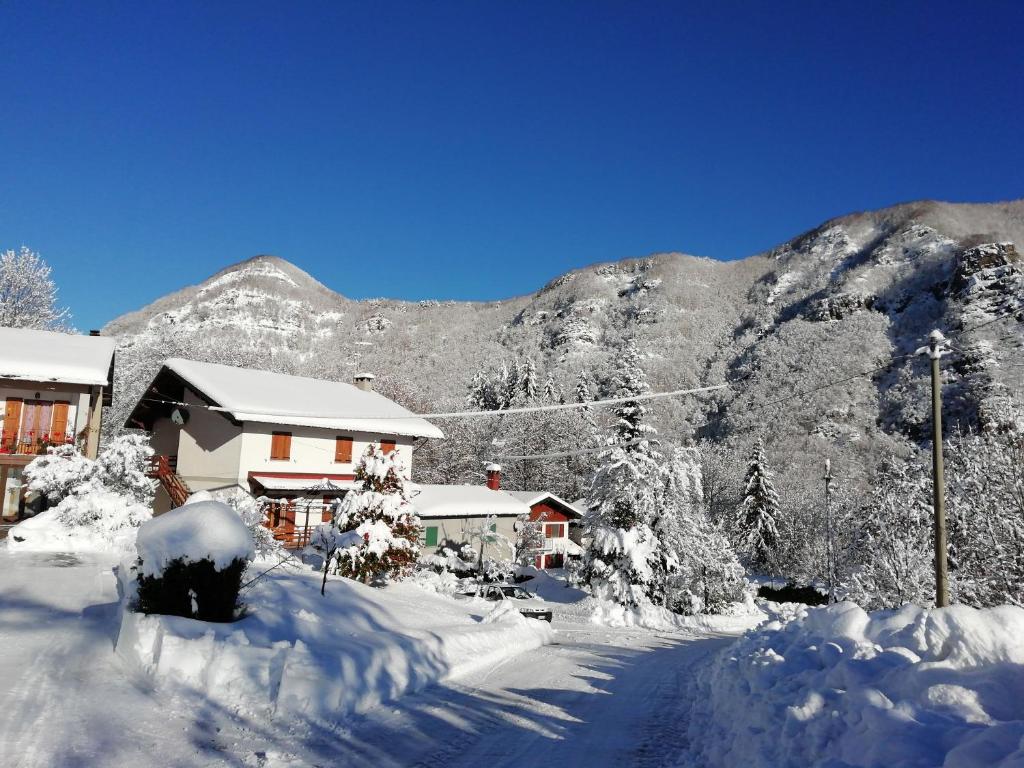 a house covered in snow in front of a mountain at Appartamento tramonto in Abetone