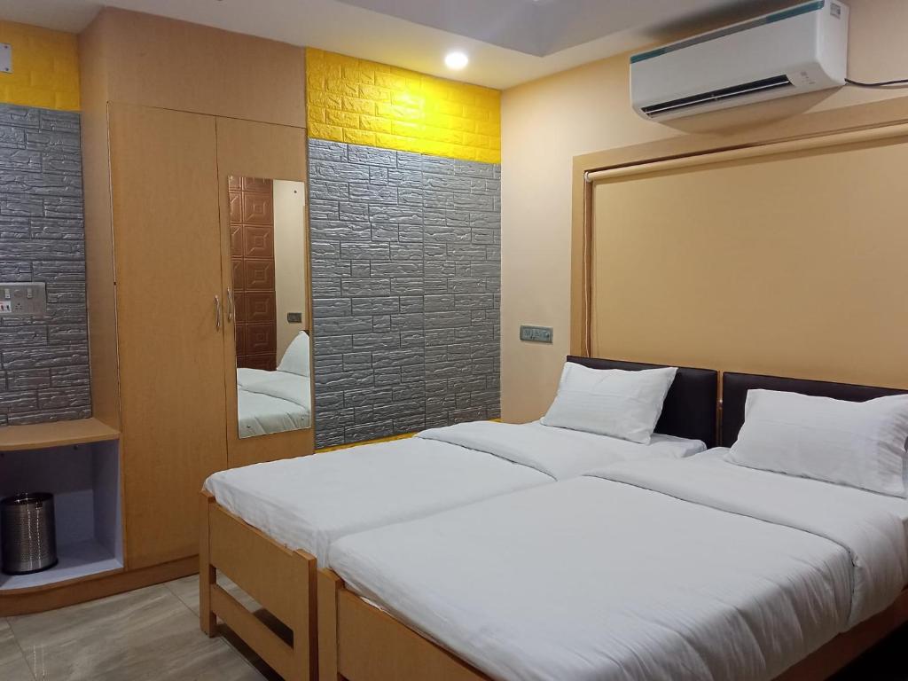 a bedroom with a large white bed and a mirror at Soukyam Hotel in Kolkata