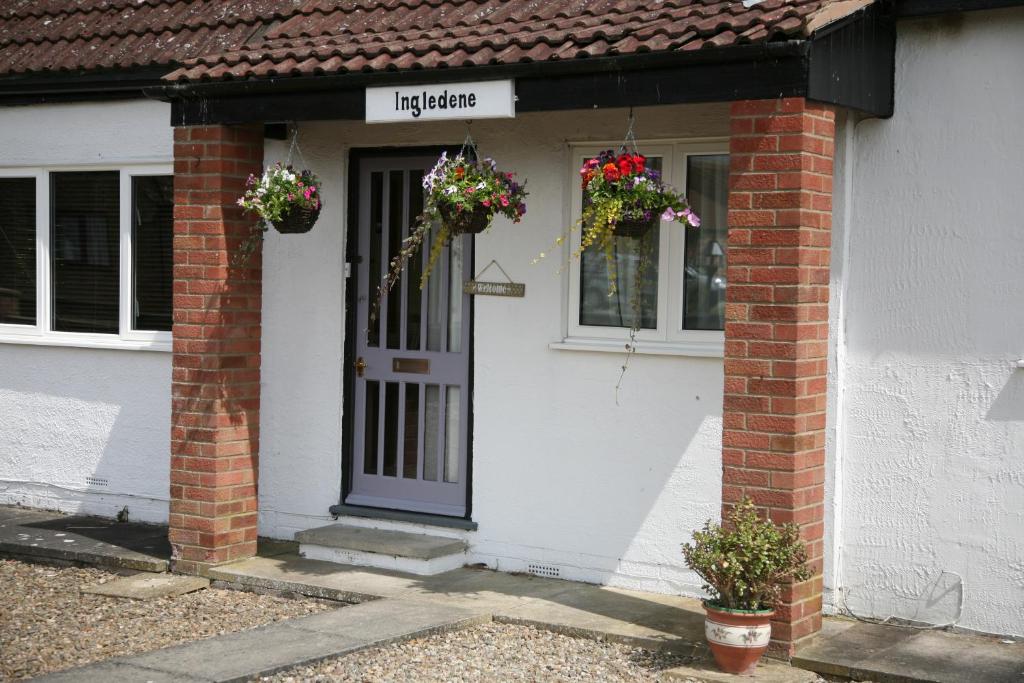 a white house with flower baskets on the door at Ingledene Room Only in Pickering